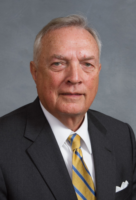 Leo, a white man with grey hair, wears a white shirt, gold tie and black jacket.