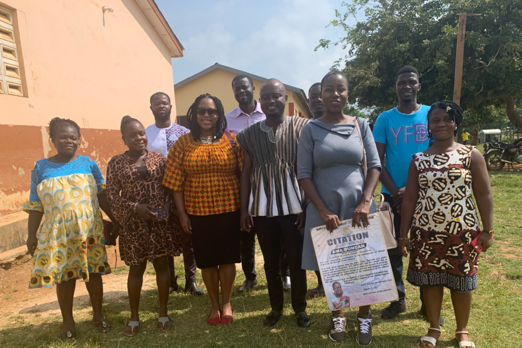 McGhee, wearing a golden blouse, stands outside with several teachers in Ghana who are Black.