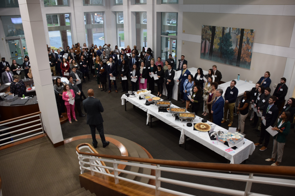 An aerial shot captures Morgan, who stands addressing a large group of law students standing in the bar center foyer.