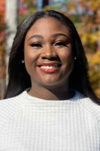 Chantrisse, a Black woman with black hair, wears a cream-colored sweater.