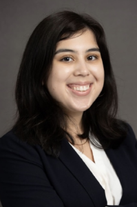 Kairy, a Hispanic/Latina woman with black hair, wears a white blouse and black jacket.