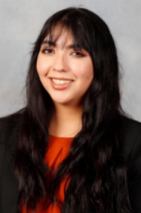 Sofia, a woan with dark brown hair, wears a red blouse and black jacket.