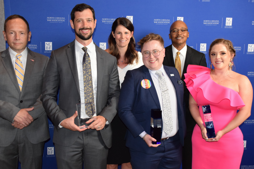Trey, a man with dark hair, wears a white shirt, grey tie, and grey suit. Collins, a person with brown hair and glasses, wears a white shirt and navy suit, and Kayla, a woman with auburn hair, wears a pink dress.