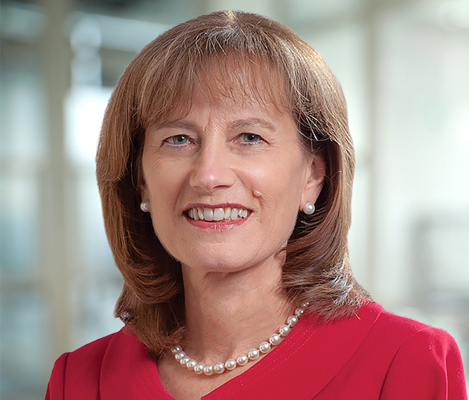 Maureen Murray is a white woman with brown hair. She wears a red dress..