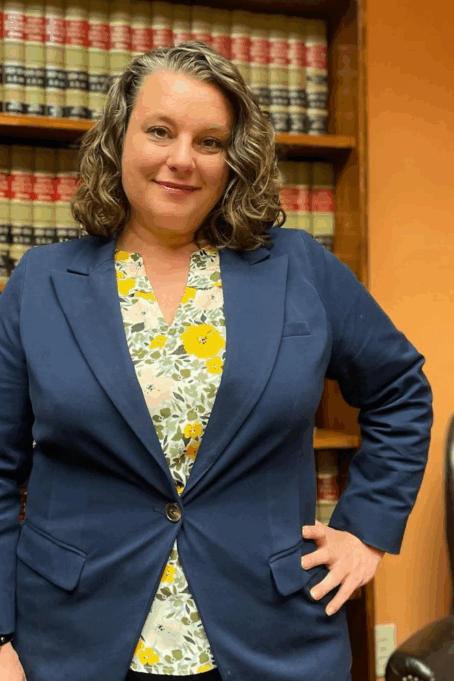 Stearns, a white woman with light brown hair, wears a yellow floral top and navy suit.
