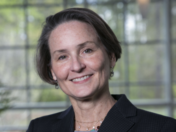 Nowlin, a woman with brown hair, wears a grey blouse and black blazer.