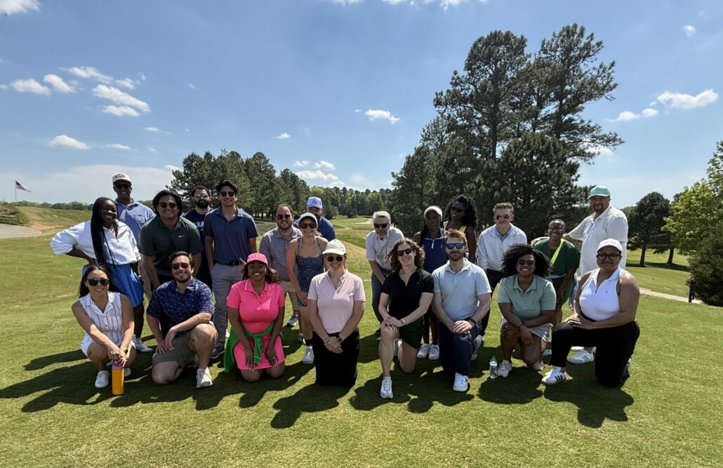 Spence, dressed in a bright pink dress and hat, is pictured with the YLD cohort outside on a golf course.